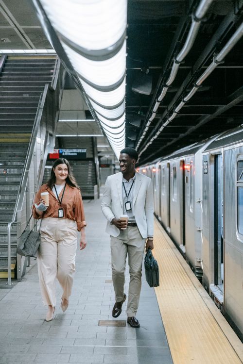 Free Two colleagues walking and conversing at a bustling subway platform. Stock Photo
