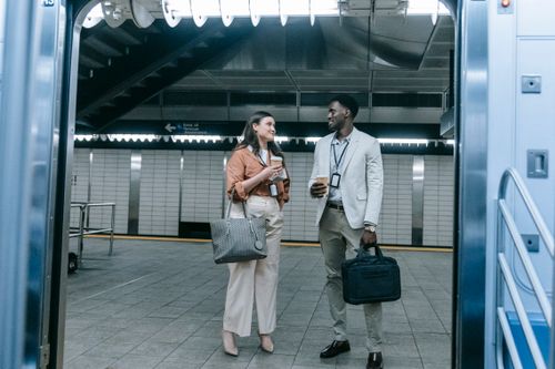 Free Two business professionals drinking coffee and talking at a subway station platform. Stock Photo