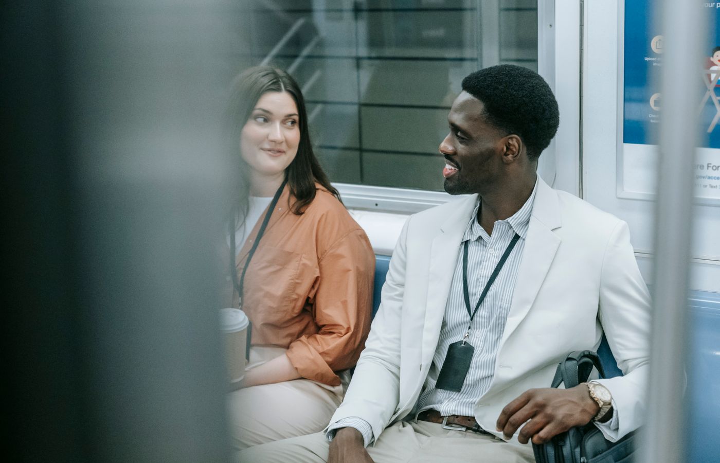 Two colleagues engage in a friendly conversation while traveling on public transportation.