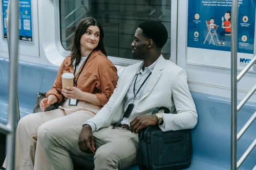 Free Two professionals chatting on a city subway train during their commute. Stock Photo