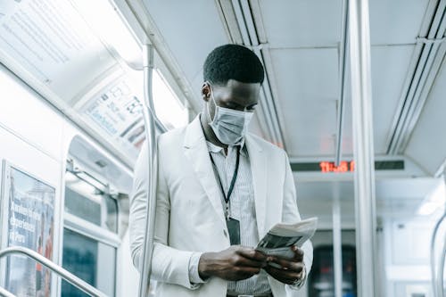 Photo of a Man Reading Newspaper Inside the Train