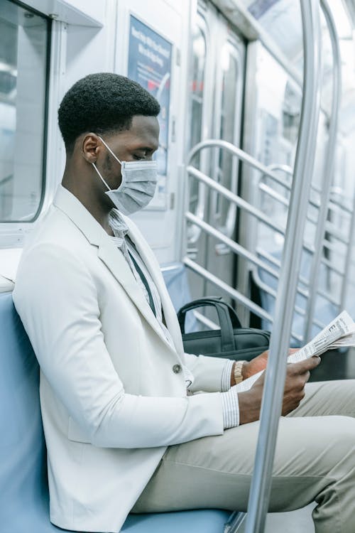 Man in Suit Jacket Reading Newspaper Inside the Train