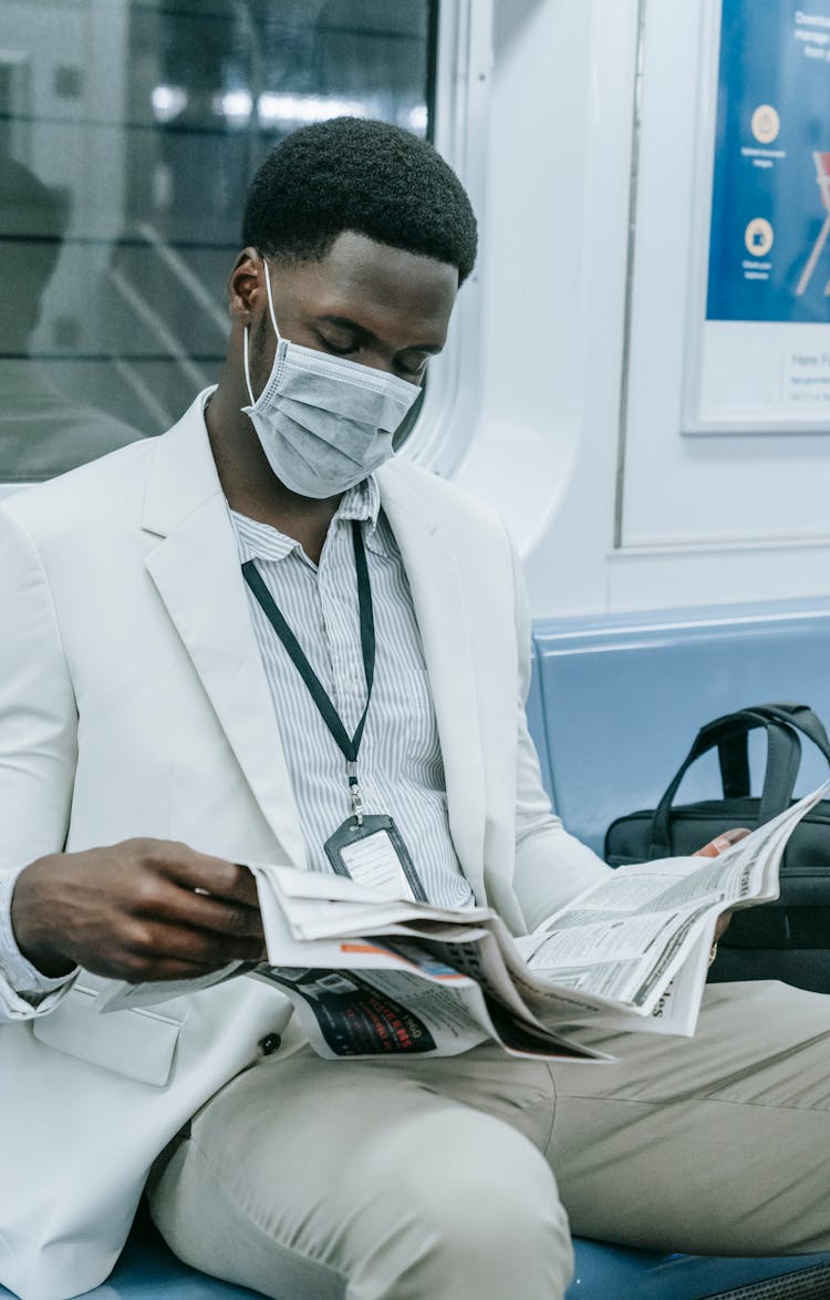 Man Wearing Face Mask Reading Newspaper Inside The Train