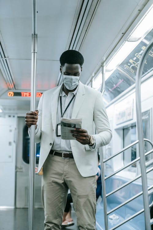 Man Reading Newspaper While Commuting