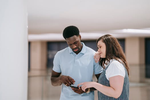 A couple indoors discussing something on a smartphone with focused expressions.