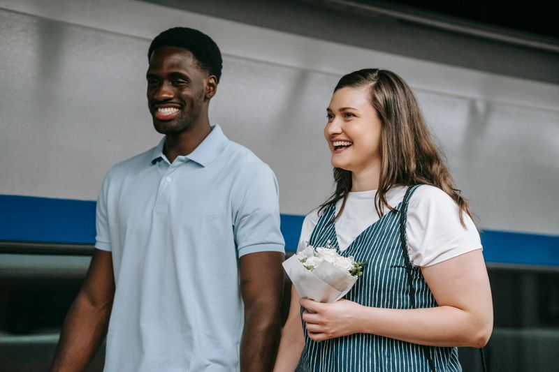 A cheerful couple holding flowers and smiling indoors