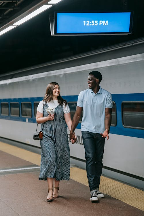 Free Couple Holding Hands While Walking on Platform Stock Photo
