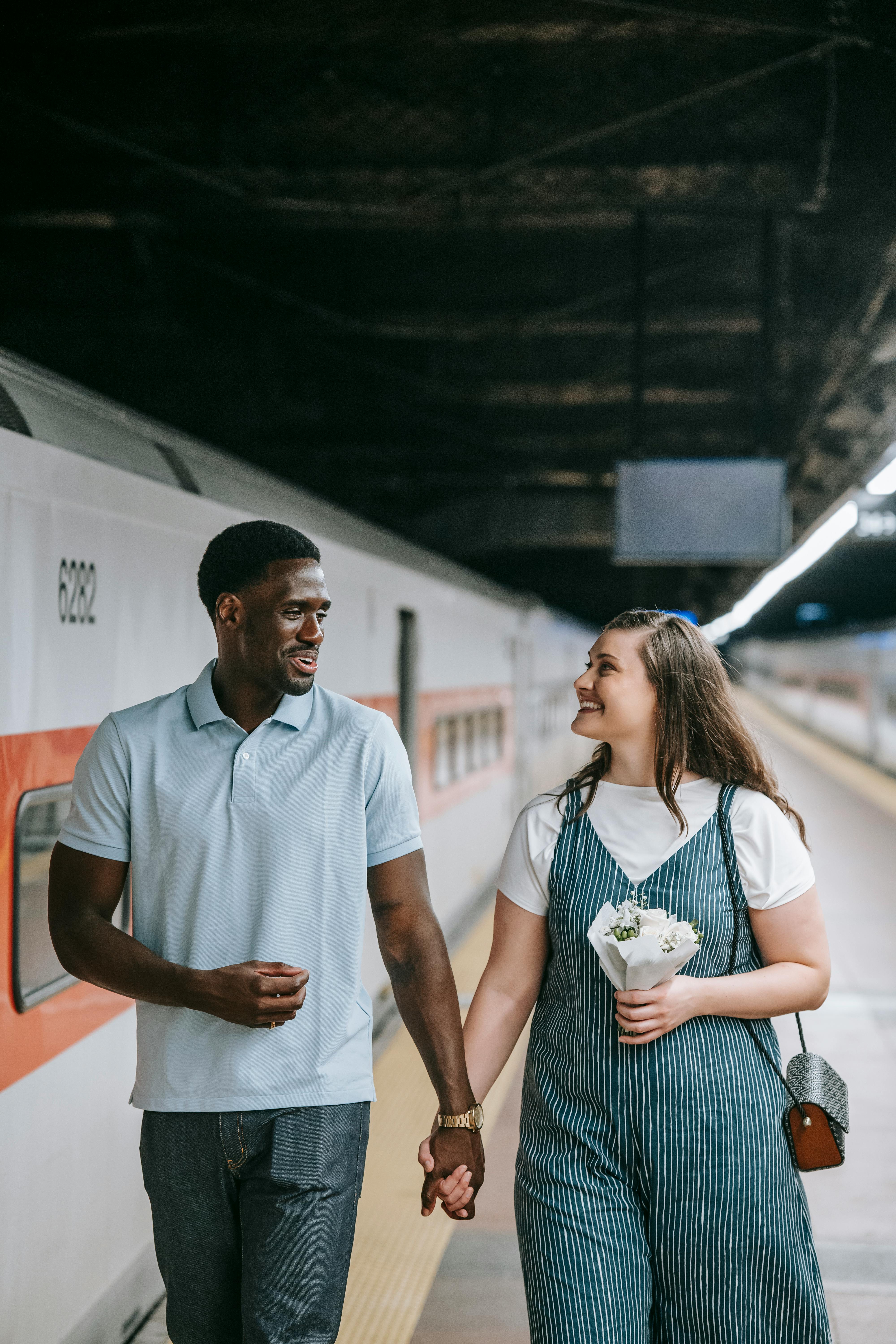 a couple walking while holding hands on the train platform