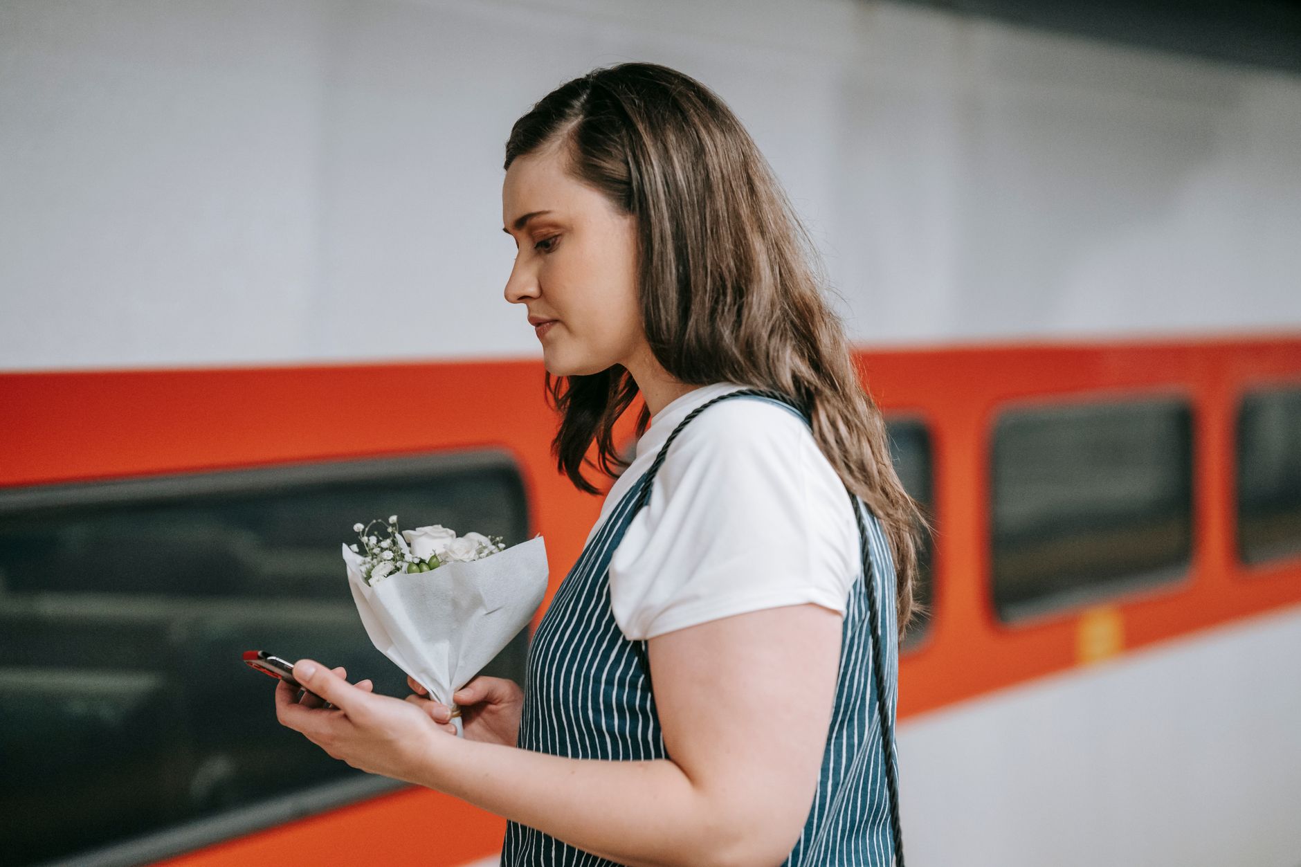 Traveler on a train platform using a phone to manage tickets (Omio vs Trainline comparison context)