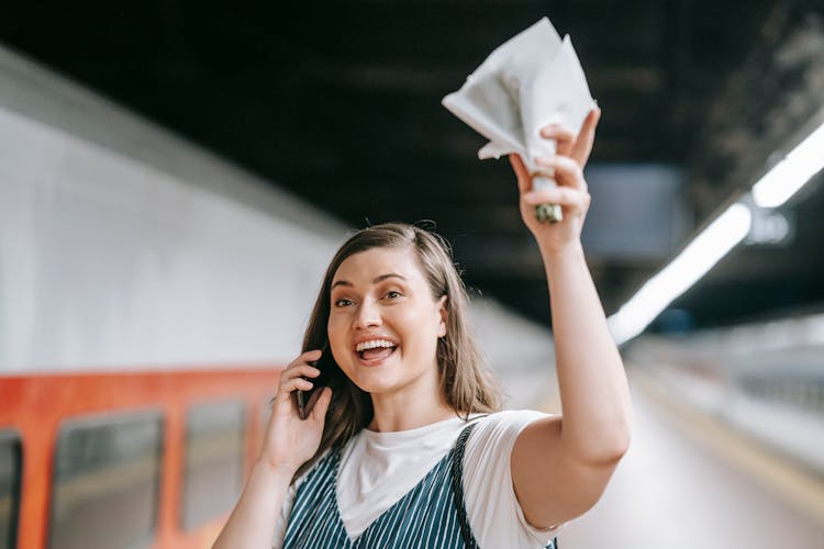 Woman Talking On The Phone And Waving Her Little Bouquet On A Train Platform 