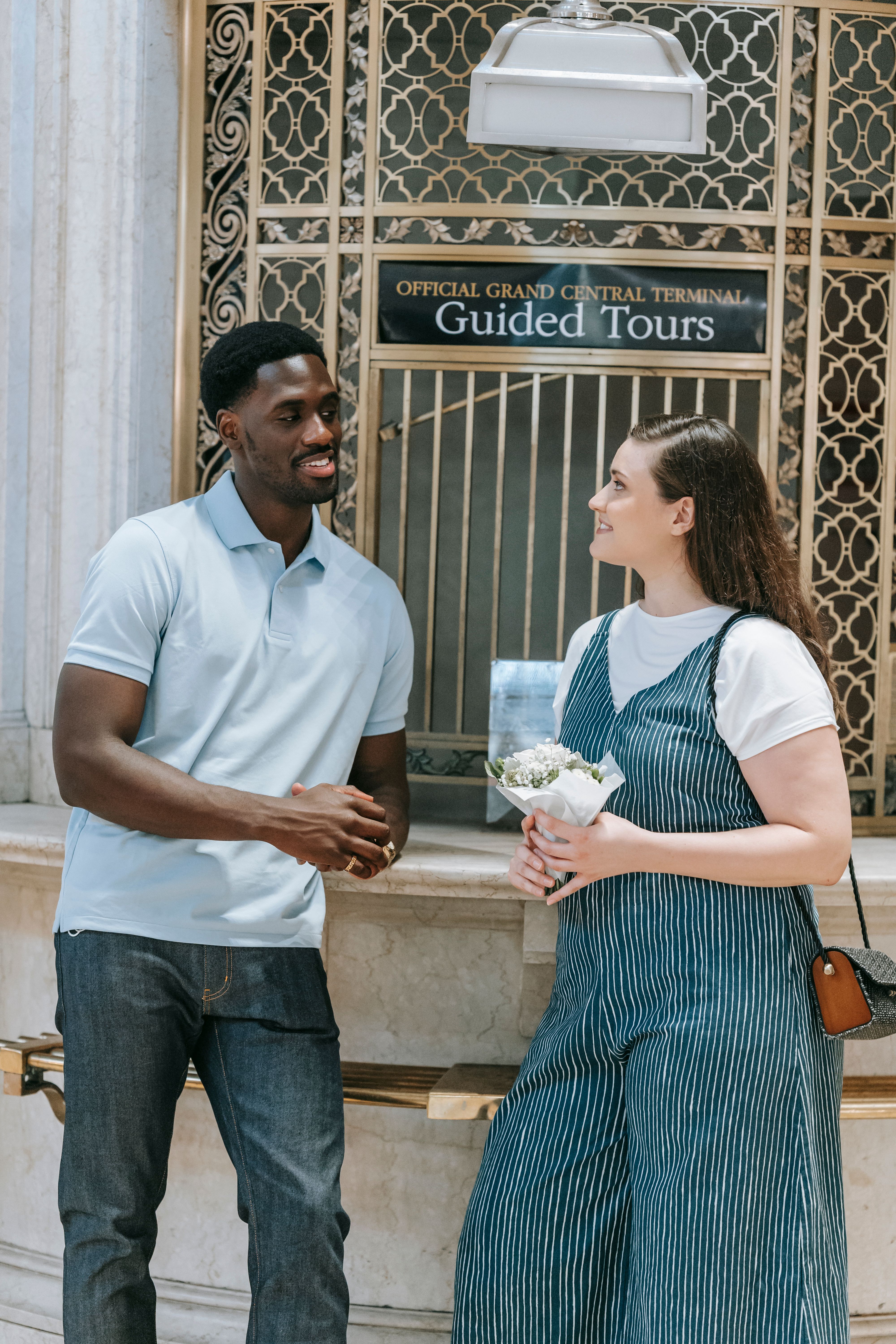 A cheerful interracial couple enjoys a conversation at Grand Central Terminal.