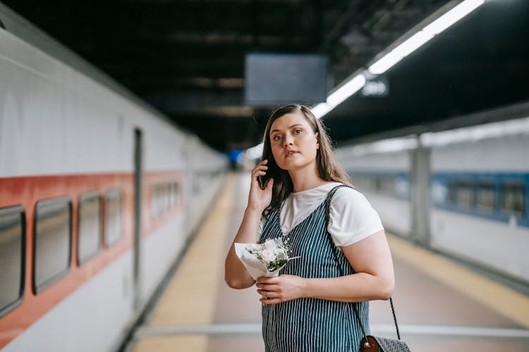 Woman Standing On Platform While Holding Flowers