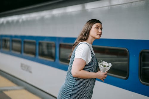 Free Woman Standing on Platform While Holding Flowers Stock Photo