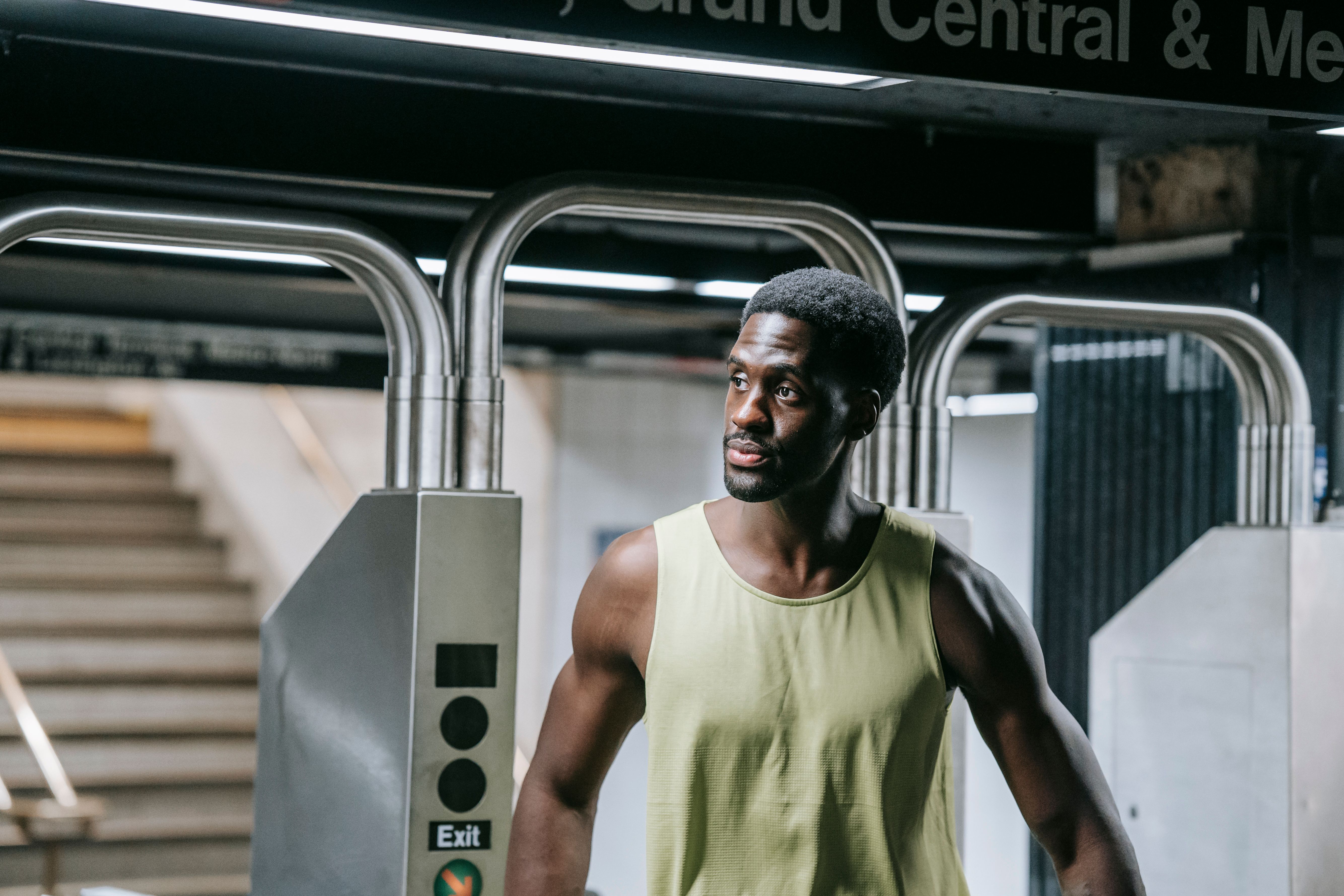 A stylish African American man stands confidently at a subway exit, embodying urban life.