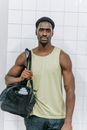 Man in Green Tank Top Carrying a Sports Bag