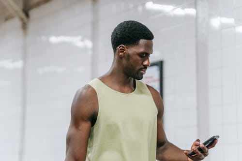Free Man in Green Tank Top Holding a Mobile Phone Stock Photo