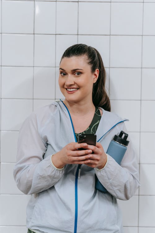 A Woman Wearing a Jacket While Using a Smartphone 