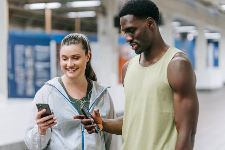 Young Man And Woman In Sports Clothing Looking At A Smartphone Screen 