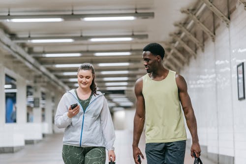 Free A Man and Woman Walking while Looking at the Phone Stock Photo