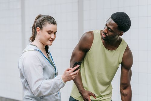 Free Two young adults enjoying a moment, sharing and looking at a smartphone together. Stock Photo