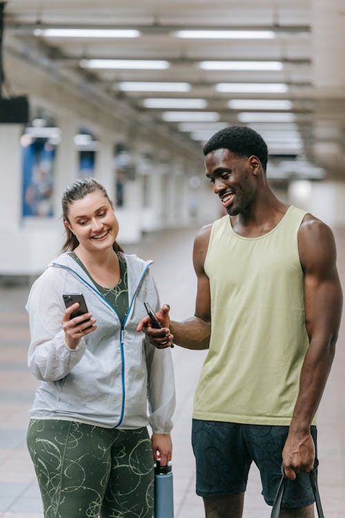 Free A Man and Woman Smiling while Looking at the Phone Stock Photo