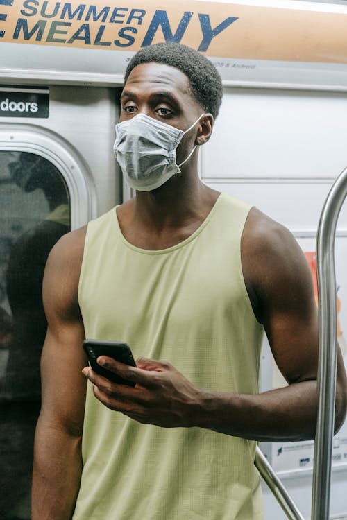 A Man Wearing Face Mask While Holding a Smartphone 