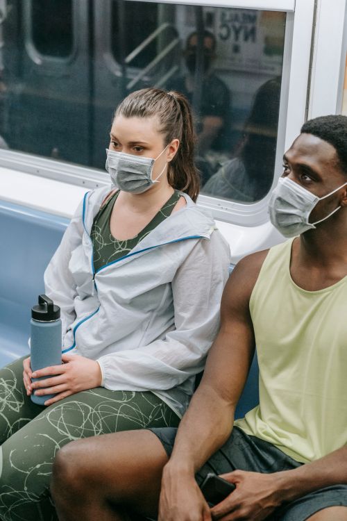 Free Two masked adults sitting on a subway during the COVID-19 pandemic. Stock Photo