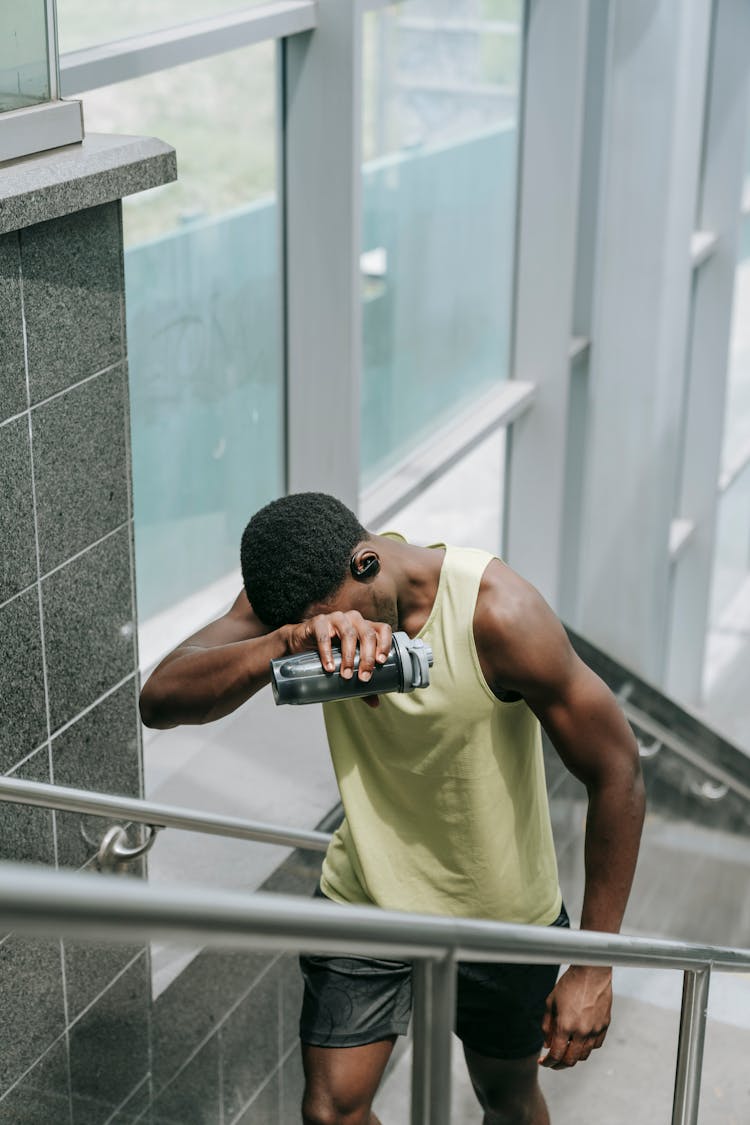 Tired Man In Sports Clothing Walking Up The Stairs After Running 