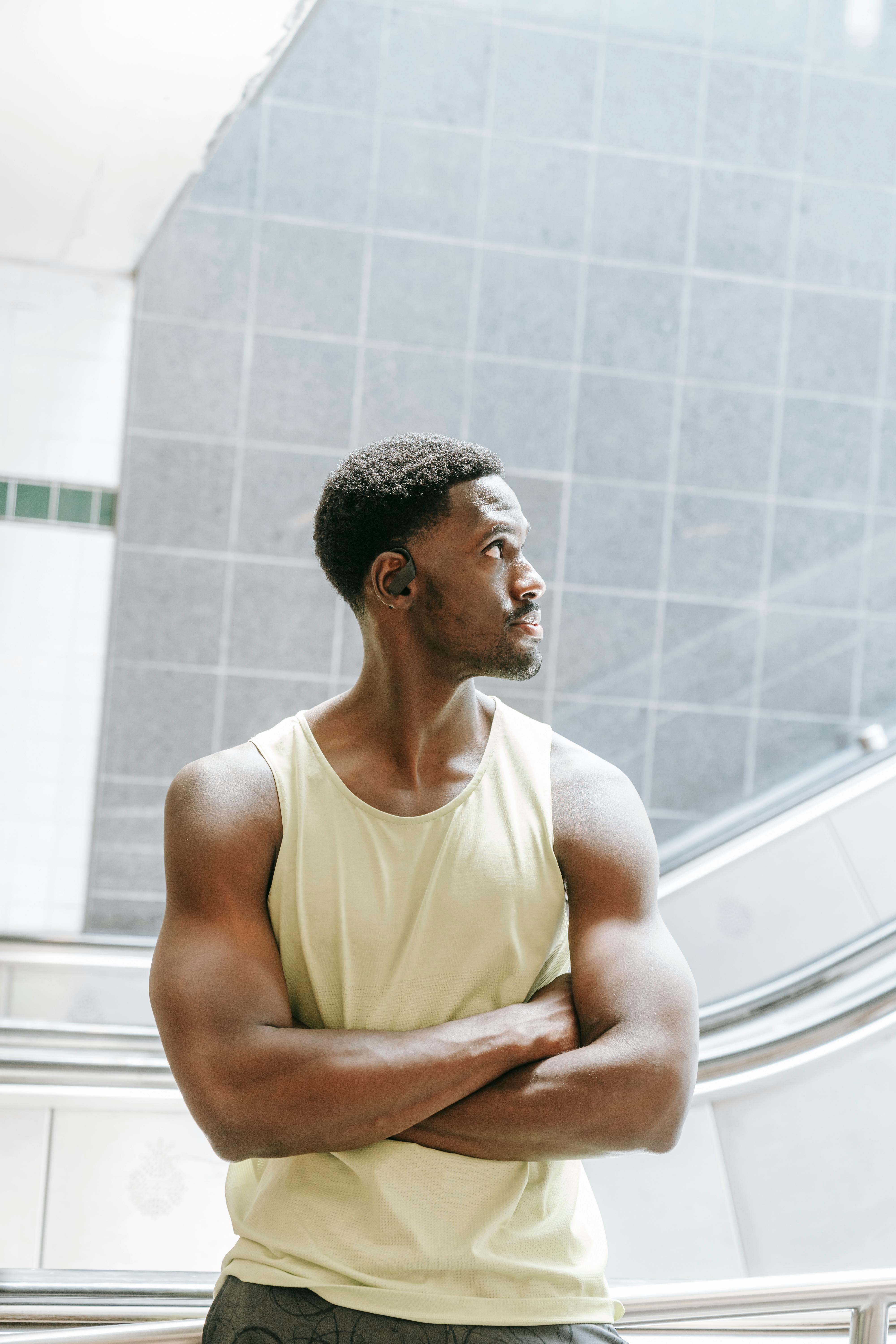 man in yellow tank top standing wearing bluetooth earphone