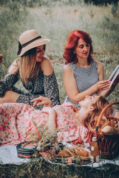 Three women enjoying a summer picnic outdoors, sharing stories and laughter in a serene setting.