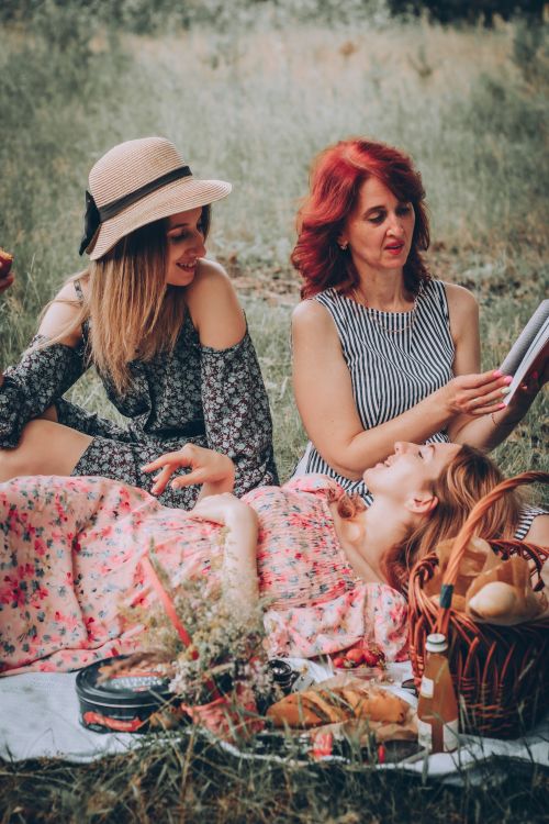 Free Three women enjoying a summer picnic outdoors, sharing stories and laughter in a serene setting. Stock Photo