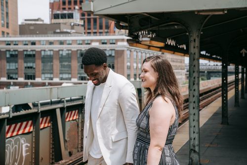 Free An interracial couple smiling and enjoying their time together on an urban train platform on a sunny day. Stock Photo