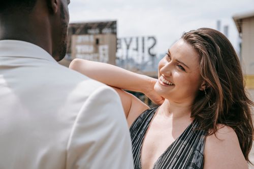 Free Woman smiling at a man outdoors in an urban setting, exuding happiness and warmth. Stock Photo