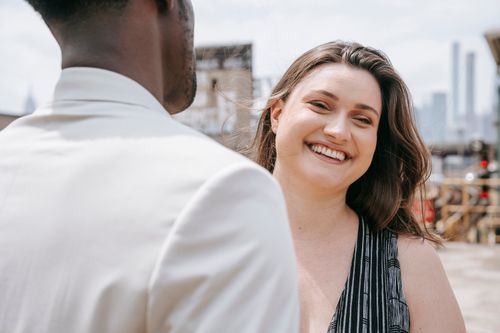 Free A joyful woman smiles while engaged in conversation outdoors on a sunny day. Stock Photo