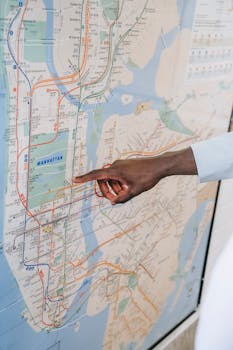 Close-up of a hand pointing at a Manhattan subway map, emphasizing transportation guidance.