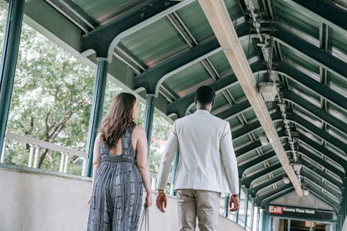 A Back View of a Man and Woman Walking on a Train Station