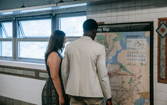 Man and woman examining New York City subway map in subway station.