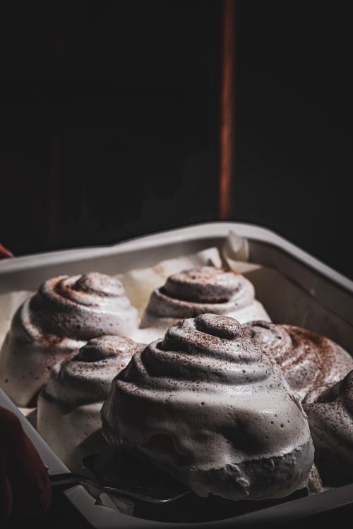 Free Close-up of cinnamon rolls with icing in a baking tray, captured with dramatic lighting. Stock Photo