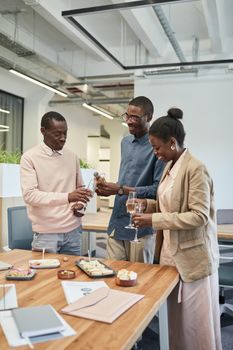 Three colleagues celebrating with champagne at an office event.