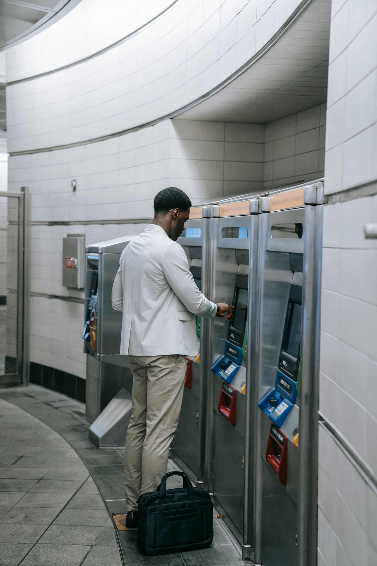 A man in business attire purchasing a ticket from a machine at a train station