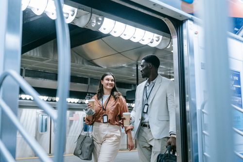 Free Two colleagues carrying cups exit a public subway train platform. Stock Photo