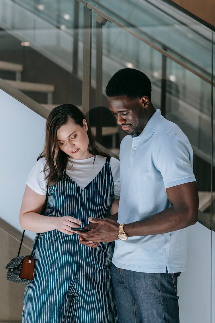 Couple Standing Together And Looking At A Smartphone Screen 