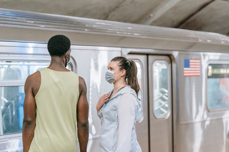 Woman Looking At A Man While Standing In Front Of A Train At The Station