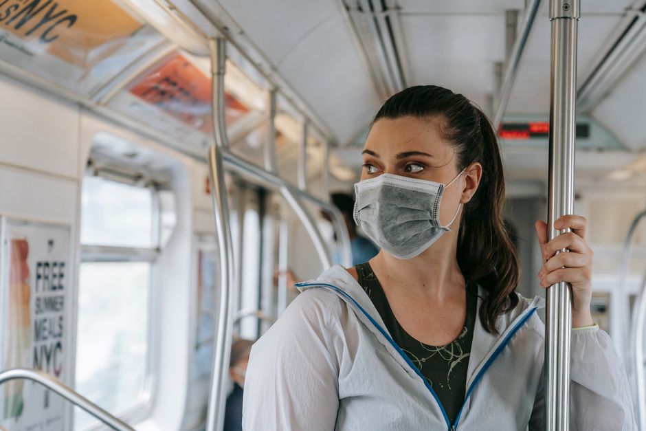 A woman wearing a face mask rides the New York City subway, emphasizing pandemic safety trends.