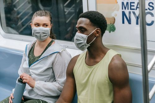Free Two commuters wearing masks sitting in a New York City subway, highlighting pandemic safety measures. Stock Photo