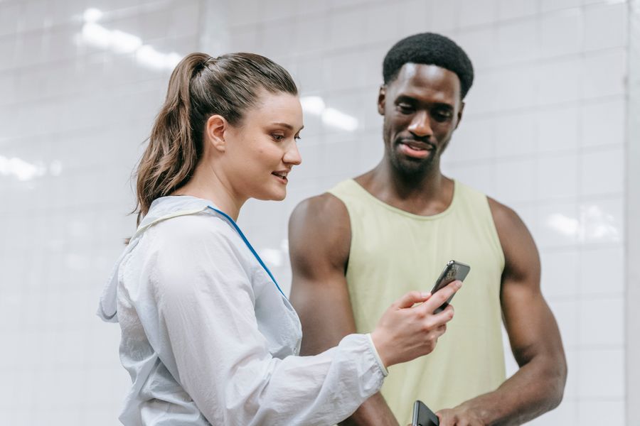A coach reviewing app data on a phone with a client — photo by Liliana Drew on Pexels