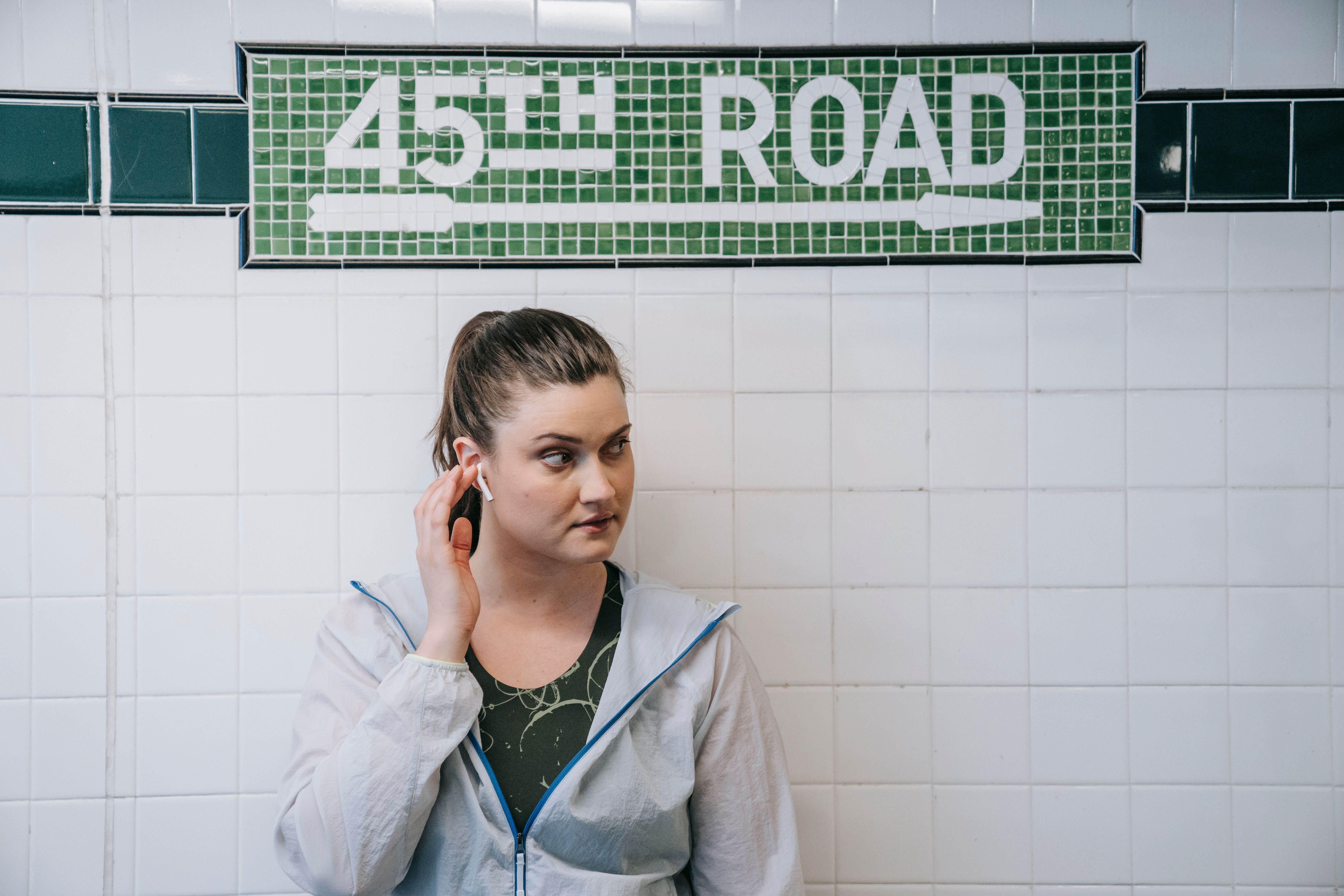 Woman listening to music with earbuds at 45th Road subway station.