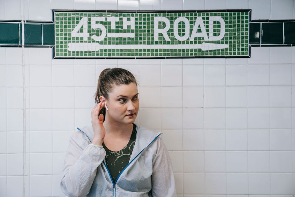 Woman listening to music with earbuds at 45th Road subway station.