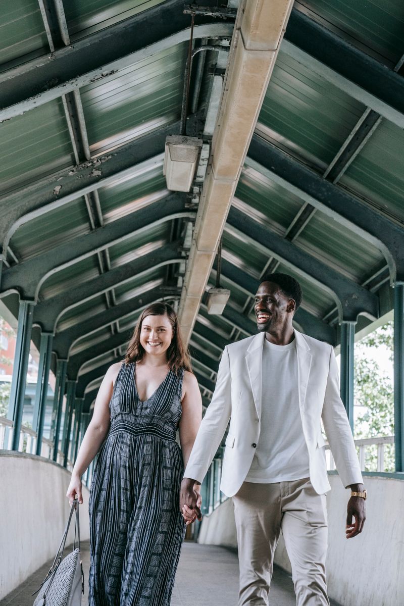 A happy couple holding hands while walking together under a covered pathway