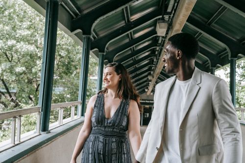 Free A smiling couple holding hands while walking in an outdoor covered passage. Stock Photo